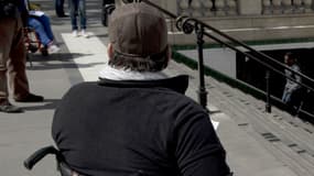 Un homme en fauteuil roulant distribue des tracts près d'un escalier de métro et invite à prendre part à une manifestation de l'Association des paralysés de France (APF) pour exiger plus d'accessibilité, le 13 mai 2014 à Paris .