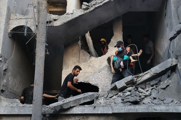 Des membres de la défense civile palestinienne et d'autres personnes transportent un enfant tué lors d'un bombardement israélien d'un bâtiment à Khan Yunis, dans le sud de la bande de Gaza, le 19 octobre 2023.