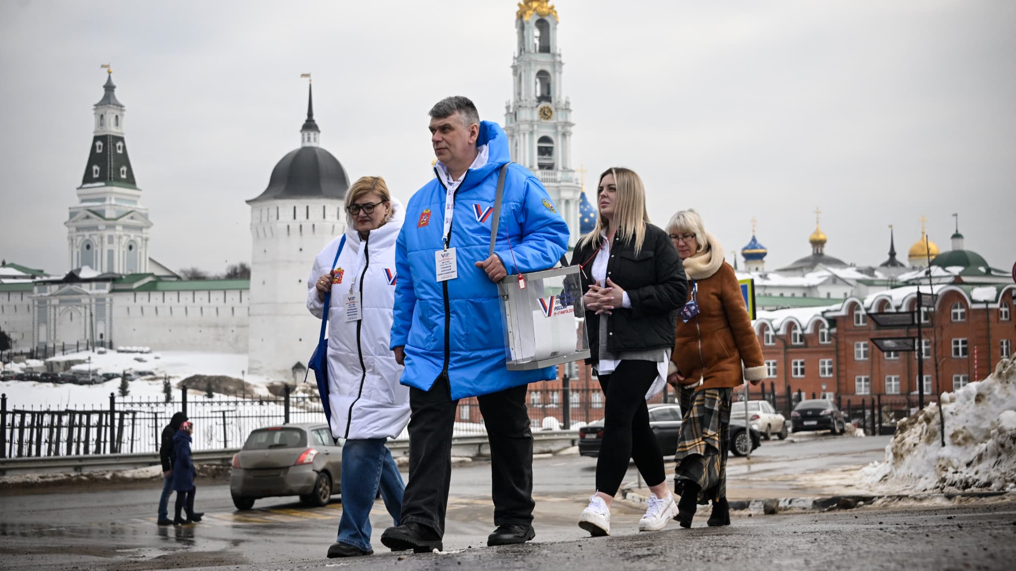 Des membres de la commission électorale marchent pour rendre visite aux électeurs à leur domicile lors de l'élection présidentielle russe à Sergiyev Posad, au nord-est de Moscou, le 16 mars 2024.