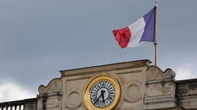 Cette photographie montre un drapeau national français flottant au-dessus d'une horloge de l'entrée de l'Assemblée nationale à Paris, le 2 juillet 2024.