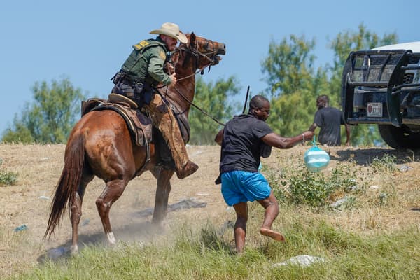 Un agent de la police des frontières américain à cheval essayant d'empêcher un homme de rejoindre le camp actuel près du fleuve Rio Grande, le 19 septembre 2021