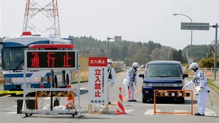 Des policiers postés à la limite du périmètre d'évacuation de 20 km autour de la centrale nucléaire de Fukushima-Daiichi renseignent des habitants quittant ce secteur (les panneaux indiquent "route bloquée" et "entrée non autorisée"). Cette zone autour de