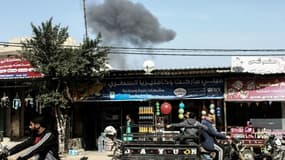Des palestiniens conduisent tandis qu'en arrière-plan une épaisse fumée s'élève vers le ciel après des frappes israéliennes en représailles à un tir de roquette sur Rafah, le 27 février 2017