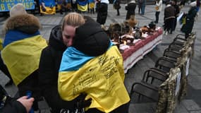 Deux femmes se réconfortent mutuellement alors qu'elles se tiennent à côté de chaises vides sur lesquelles sont accrochés des uniformes de soldats, près d'une table de Noël symbolique dressée avec des plats traditionnels, lors d'un rassemblement en soutien aux prisonniers de guerre et aux soldats disparus à Lviv le 21 décembre 2024. (Photo d'illustration)