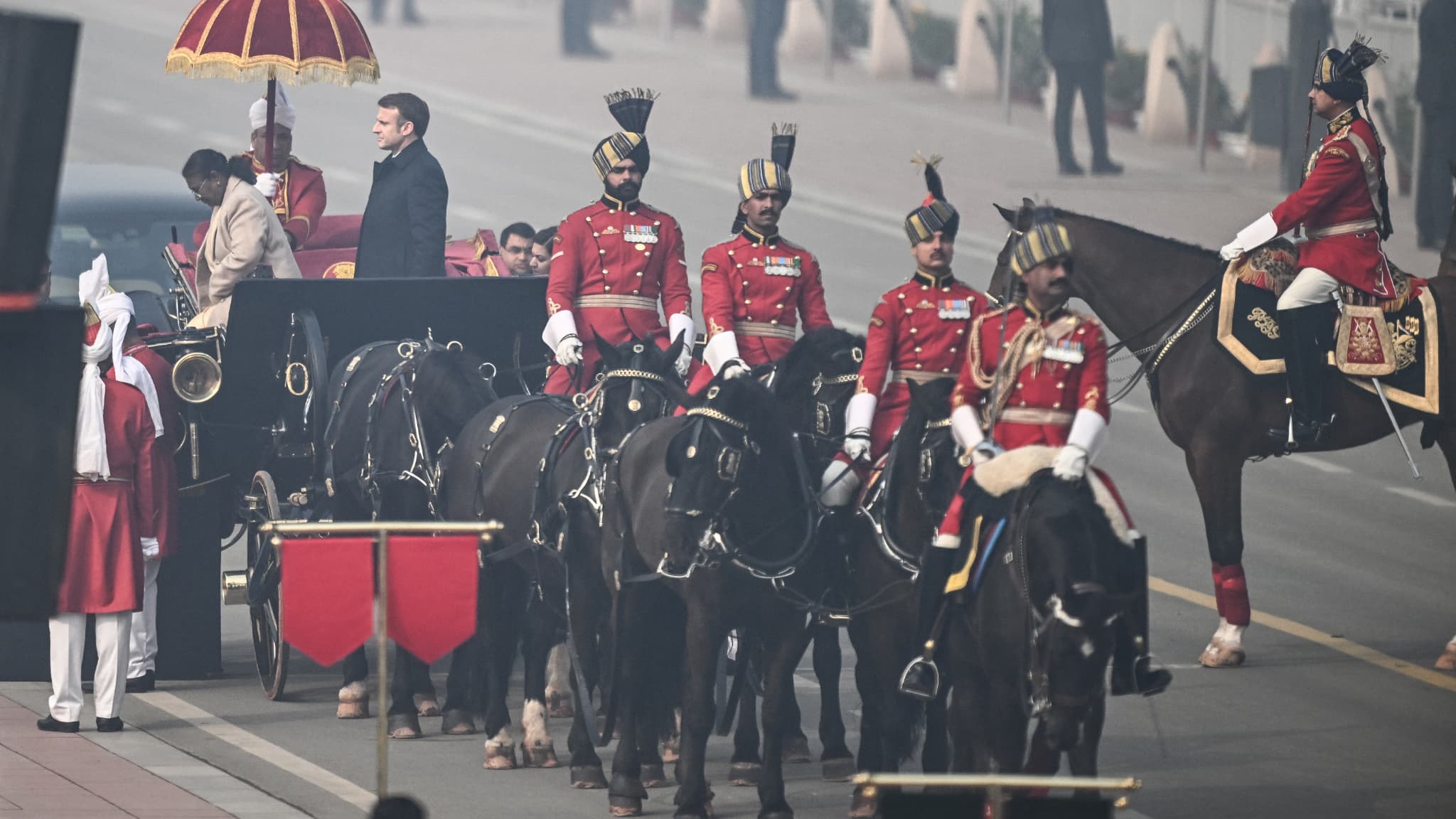 Le président indien Droupadi Murmu (G) et l'invité d'honneur, le président français Emmanuel Macron (C,D), arrivent pour assister au défilé du 75e jour de la République de l'Inde à New Delhi, le 26 janvier 2024.