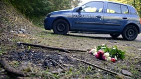 Un véhicule de gendarmerie et un bouquet de fleur à l'emplacement de la tuerie de Chevaline le 8 septembre 2012