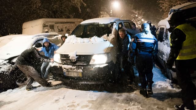 Des automobilistes tentent de déplacer un camion coincé dans la neige, le 7 février 2018 à Bièvres (Essonne)