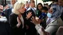 Marine Le Pen, candidate RN à la présidentielle, discute avec une femme portant un foulard, sur un marché de Pertuis, le 15 avril 2022 dans le Vaucluse