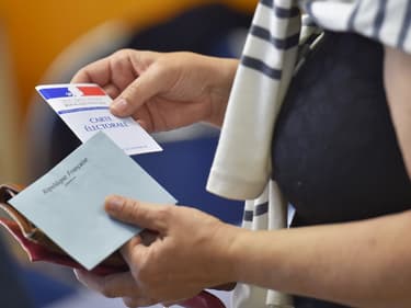 Une femme, carte électorale et enveloppe de vote à la main (Photo d'illustration).