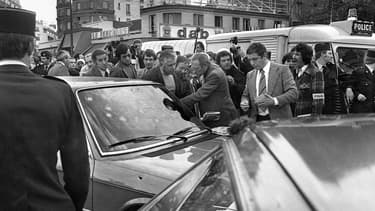 Des policiers entourant la voiture criblée de balles de Jacques Mesrine en 1979 à Paris. 