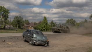 Un obusier automoteur ukrainien 2S1 Gvozdika passe devant une voiture endommagée sur une route du district de Vovchansk, dans la région de Kharkiv, le 12 mai 2024, dans le contexte de l'invasion russe de l'Ukraine.