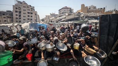 Des Palestiniens portant des casseroles pour recevoir des repas chauds, dans la ville de Gaza, le 23 juillet 2025.