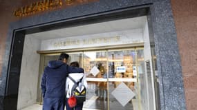Des personnes se tiennent devant l'entrée fermée du grand magasin Galleries Lafayette à Paris, le 14 novembre 2015. (Illustration)