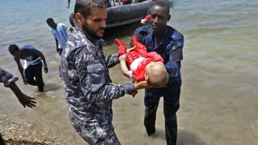 Le corps d'un des trois bénés repêchés vendredi après le naufrage d'une embarcation est porté par des membres des forces de sécurité libyennes, le 29 juin 2018 à al-Hmidiya