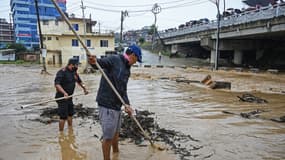 Des habitants nettoient une rue inondée après le débordement de la rivière Balkhu pendant les pluies de mousson à Katmandou le 28 septembre 2024