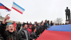 A Simferopol, en Crimée, des activistes pro-russes brandissent samedi un drapeau russe géant près d'une statue de Lénine