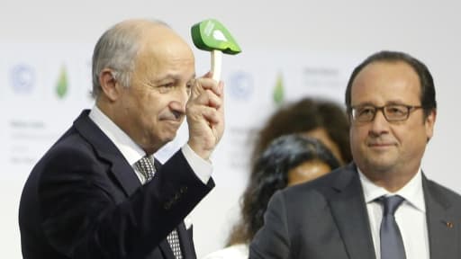 Le président de la COP21 Laurent Fabius donne un coup de marteau symbolique pour marquer l'officialisation de l'accord sur le climat, au côté du président français François Hollande, le 12 décembre 2015 au Bourget