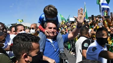 Le président brésilien Jair Bolsonaro porte le fils d'un de ses partisans lors d'un rassemblement à Brasilia le 31 mai 2020