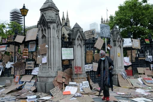 Une femme marche au travers de pancartes gisant au sol après une manifestation de solidarité avec le mouvement américain Black Lives Matter, à Londres le 7 juin 2020 Une femme marche au travers de pancartes gisant au sol après une manifestation de solidarité avec le mouvement américain Black Lives Matter, à Londres le 7 juin 2020