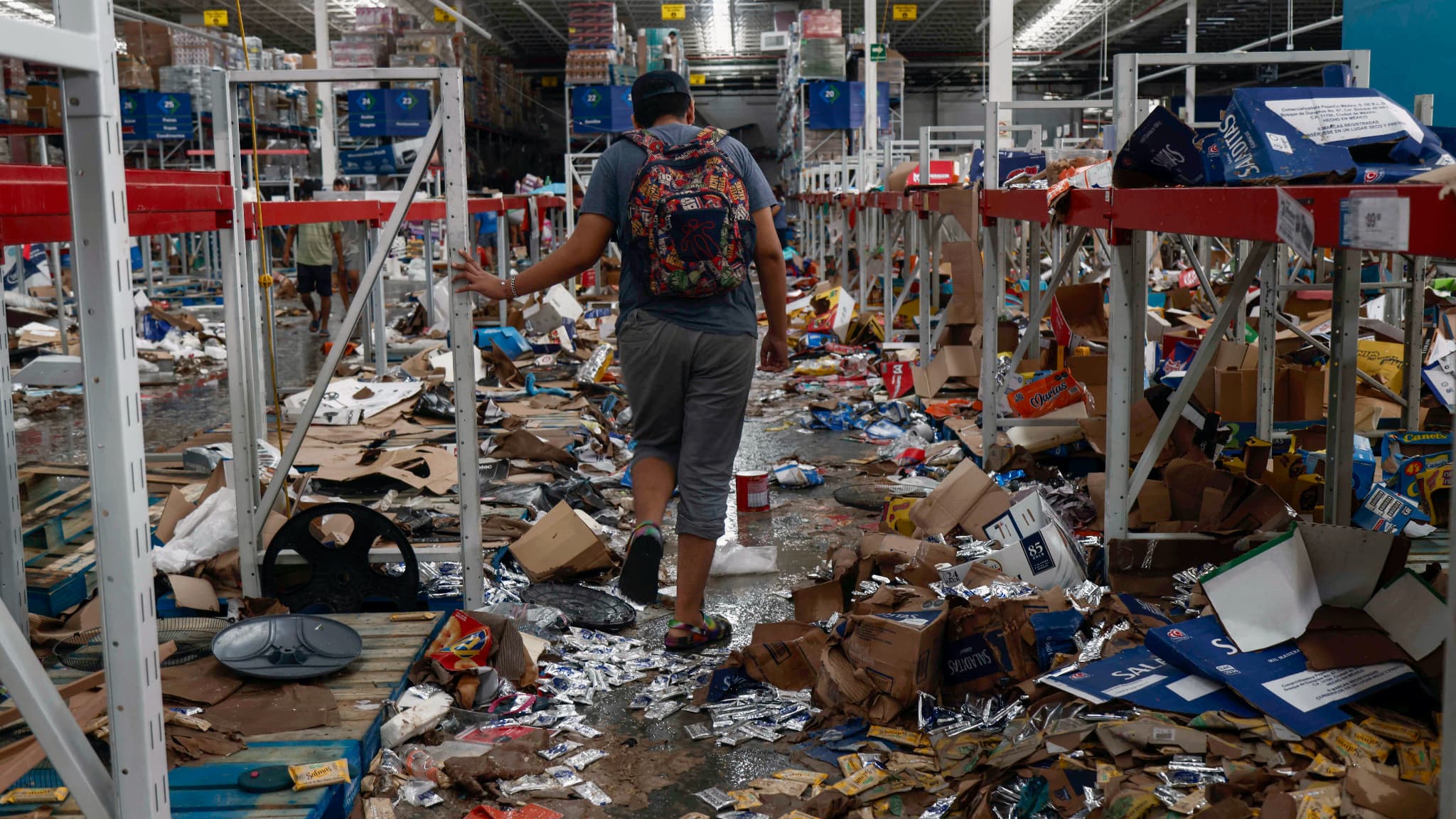 Un homme marche sur un supermarché pillé après le passage de l'ouragan Otis à Acapulco, dans l'État de Guerrero, au Mexique, le 26 octobre 2023.