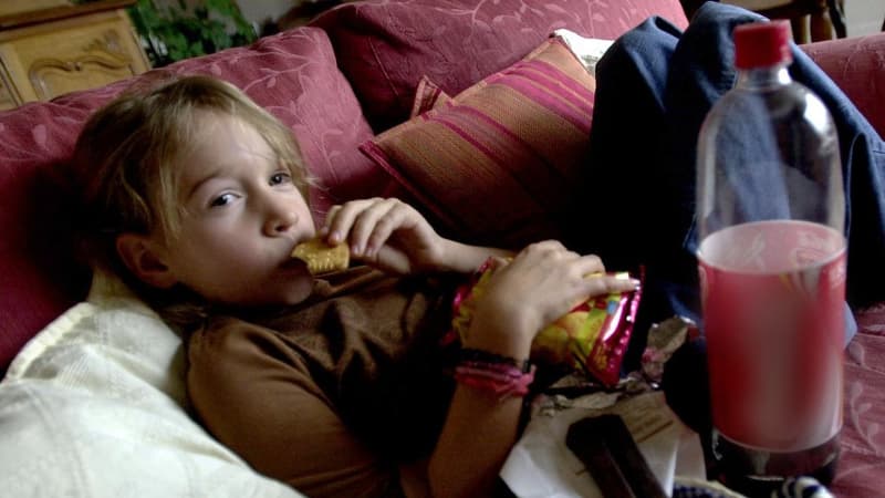 Une petite fille mange un biscuit en regardant la télévision, le 30 octobre 2003 à Caen (photo d'illustration)