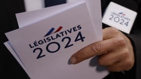 Un journaliste tient des cartes marquées « Législatives 2024 » lors de la soirée électorale du parti au pouvoir Renaissance alors que les résultats du premier tour des élections législatives sont attendus à Paris le 30 juin 2024