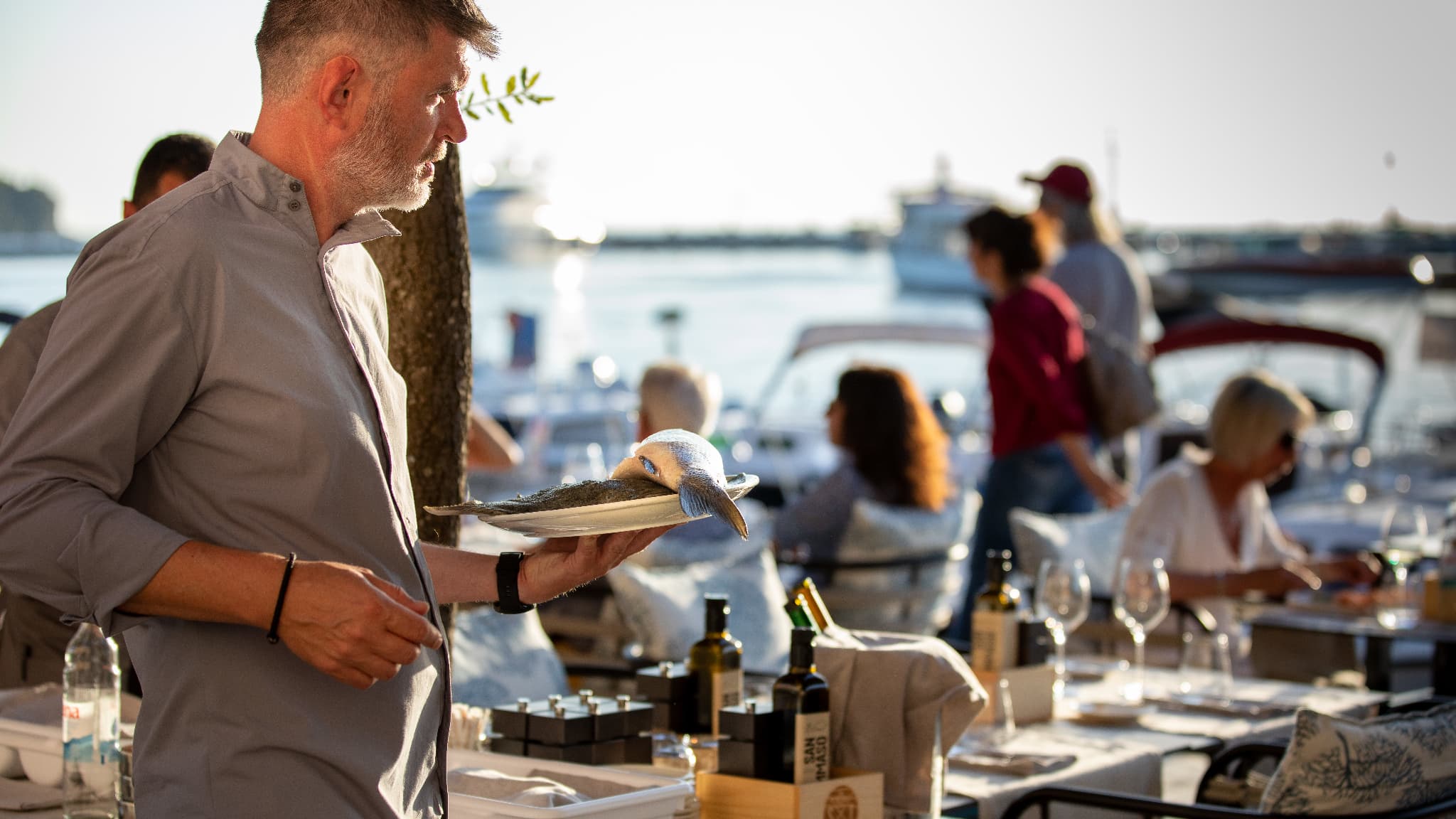 Un serveur en train de servir du poisson à une terrasse ensoleillée en mars 2023.