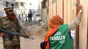 Une employée du bureau de recensement, accompagnée par un soldat, marque une maison après avoir recueilli les informations nécessaires, le 15 mars 2017 à Karachi, au Pakistan