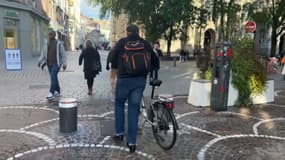 Un homme marchant à côté de son vélo dans le centre-ville de Lille (Nord) début novembre 2023.