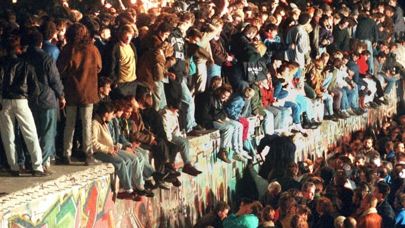 Des Allemands assis sur le Mur de Berlin, le 11 novembre 1989.