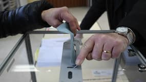 Un électeur place son enveloppe dans une urne.