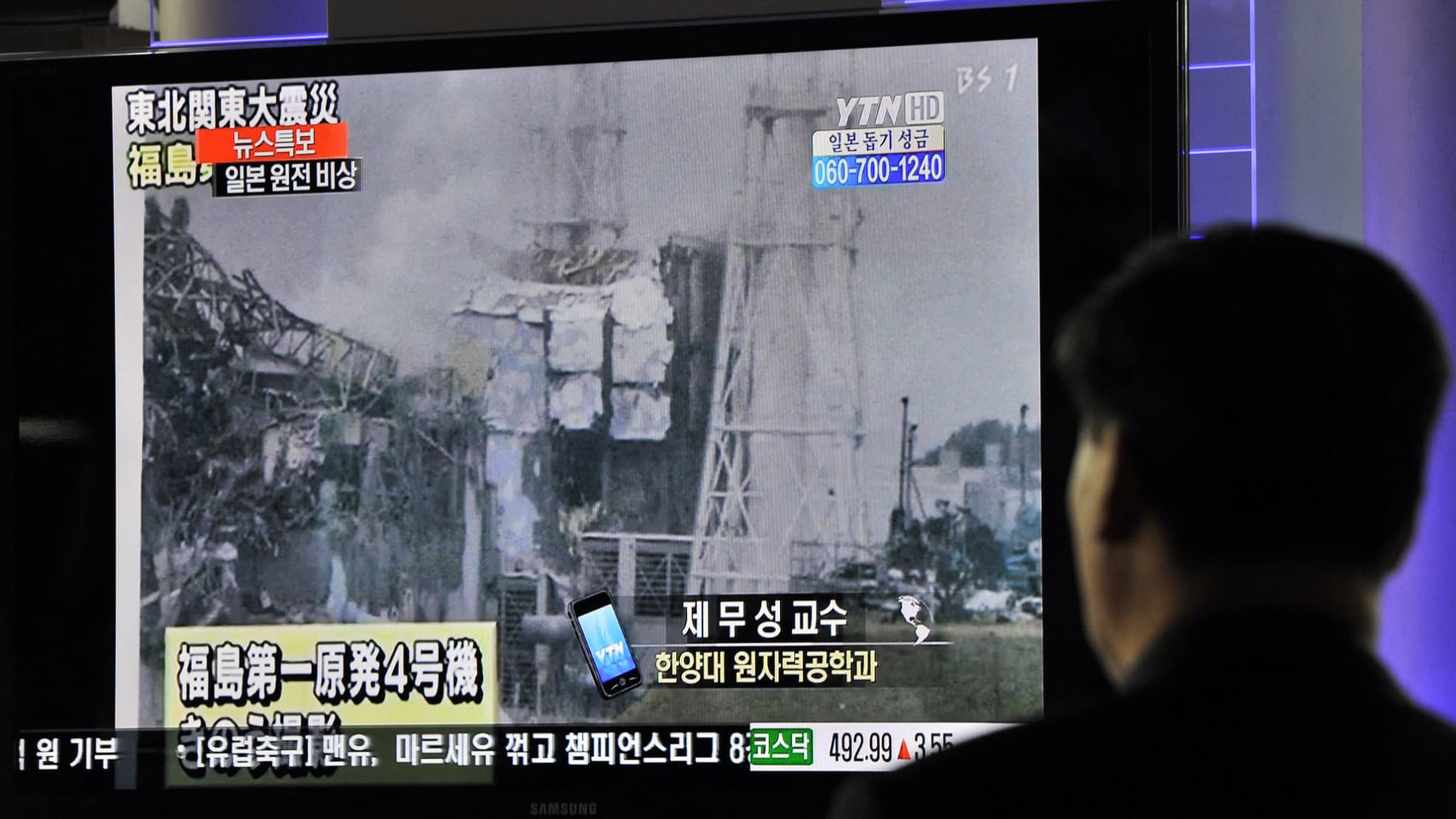 Des passagers sud-coréens passent devant un écran de télévision annonçant l'explosion et la fusion de la centrale nucléaire de Fukushima-Daiichi (au Japon) après un violent séisme, dans une gare ferroviaire de Séoul (Corée du Sud), le 16 mars 2011. (Photo d'illustration)
