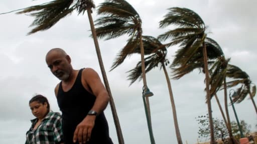 A couple walks through a debris-covered road in Fajardo, Puerto Rico