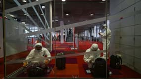 Des passagers chinois en combinaison intégrale de protection contre le Covid-19 attendent leur vol pour Shanghai à l'aéroport de Roissy, le 17 janvier 2022 près de Paris