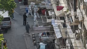 Des personnels chinois devant un immeuble dans un district de Shanghai