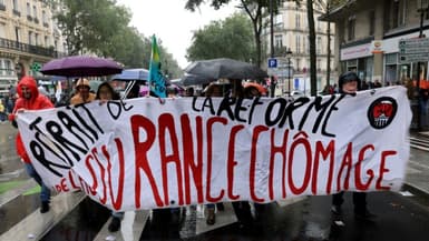 Des manifestants portent une banderole pour le retrait de la réforme de l'assurance chômage le 5 octobre 2021 à Paris