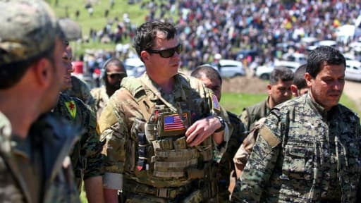 Un officier américain, de la coalition dirigée par les États-Unis, parle avec des combattants des unités de protection du peuple kurde (YPG) au nord-est de la ville kurde syrienne de Derik, connue sous le nom d'al-Malikiyah, le 25 avril,...