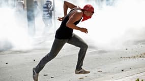 Un manifestant brésilien, jeudi, tente d'échapper aux gaz lacrymogènes des policiers.