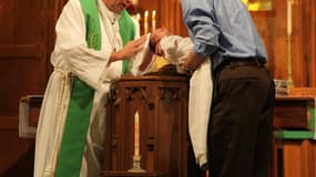 Un religieux en train de baptiser un nourrisson dans un église (Photo d'illustration).