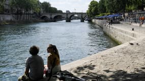 Un couple assis sur les bords de Seine, à Paris le 9 juillet 2022 (photo d'illustration)