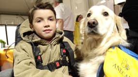Le petit Adrien Derudder, jeune myopathe porte-parole de la 20e édition du Téléthon, pose en compagnie de son chien Willy, le 8 décembre 2006 à Paris.