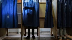 Des électeurs s'isolent avant de voter dans un bureau, dimanche 24 avril 2022, pour le second tour de l'élection présidentielle