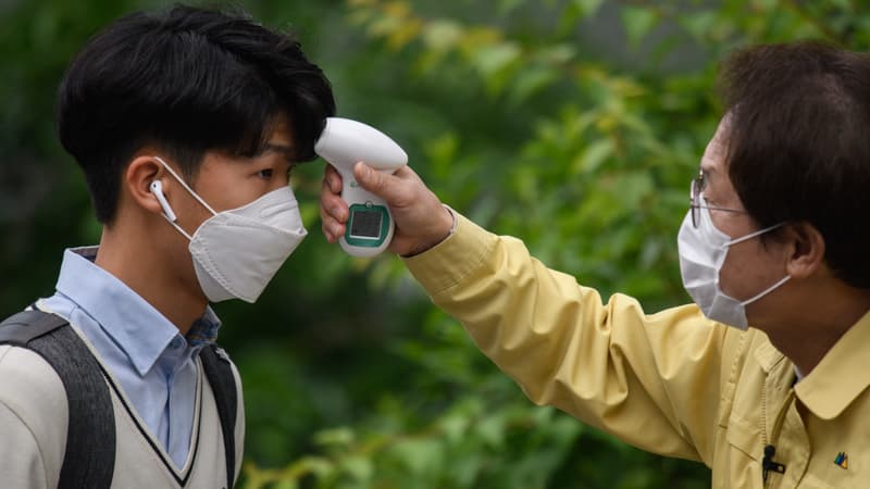 Un homme contrôle la température d'un étudiant à Séoul (Corée du Sud), en raison des craintes liées au coronavirus, le 20 mai 2020.