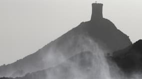 Des gens marchent le long d'un sentier piétonnier avec la Parata Genovese Tour (arrière-plan) sur le phare des Iles Sanguinaires, le long de la côte d'Ajaccio, alors que des vents forts et des vagues frappent la côte pendant la tempête Franklin, sur l'île méditerranéenne française de Corse, le 21 février 2022.