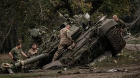 Des soldats ukrainiens s'approchant d'un tank russe abandonné le 30 septembre 2022 à Kyrylivka, en Ukraine