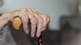 Main d'une personne âgée tenant une canne. (photo d'illustration)