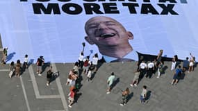 Des militants du groupe environnemental international Greenpeace déploient une banderole géante affichant une photo de Jeff Bezos et indiquant "Si vous pouvez louer Venise pour votre mariage, vous pouvez payer plus d'impôts" sur la place Saint-Marc à Venise le 23 juin 2025.