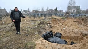 Un homme se tient près d'une fosse commune à Boutcha, près de Kiev, le 3 avril 2022