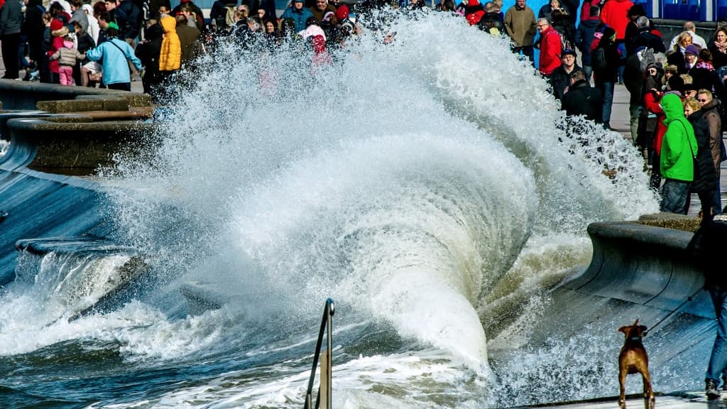Des personnes se rassemblent pour regarder les vagues se briser sur la digue à Wimereux, dans le nord de la France, le 21 mars 2015.