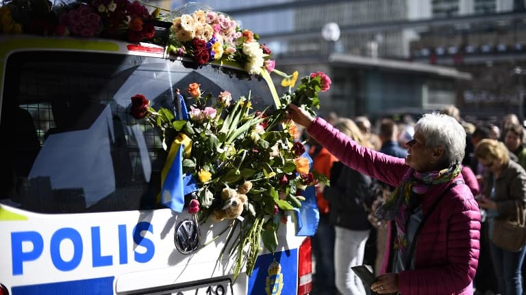 Une femme dépose des fleurs sur une voiture de la police suédoise à Stockholm dimanche 9 avril